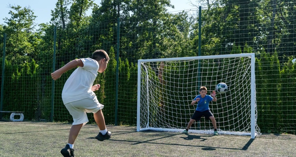 Coach training a young football player on the pitch